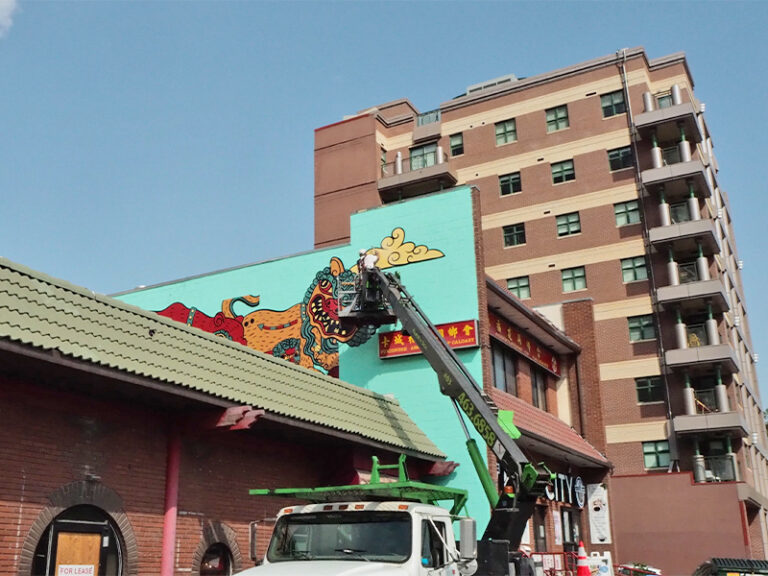 A colour mural panel of a bison and dragon is installed on an outdoor wall in Chinatown.