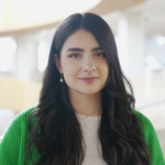 Natalia Ionescu with long dark hair wearing a white shirt and green cardigan