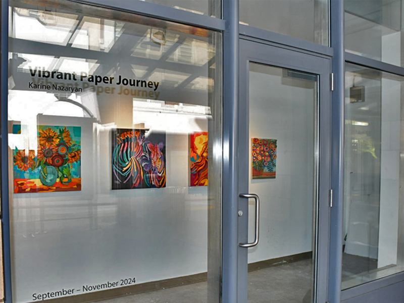 A view through the window of the Open Spaces galleries showing paper artworks by Karine Nazaryan