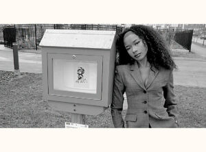 Kamika Guerra Walker beside her mini gallery, which displays a portrait artwork.