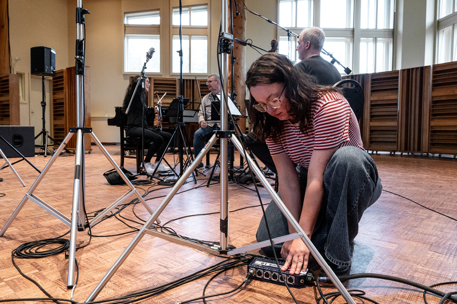 Photo of audio engineer at work with equipment and performers with instruments nearby