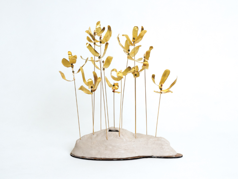 Brass, jasper and shell bead artwork by Victoria Sanchez of a golden plant with stems on a small mound.