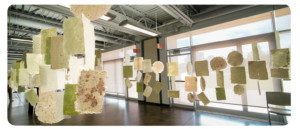 Handmade paper sheets hang from the ceiling in an indoor space.