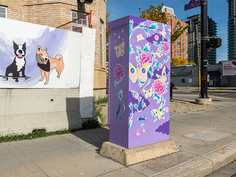 A purple utility box decorated with vibrant butterflies and flowers near a mural of a dog and a skateboarder.