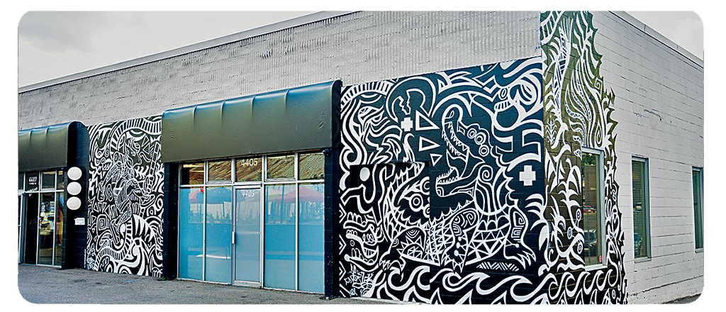 A strip mall building with public art mural wrapping the one-story building