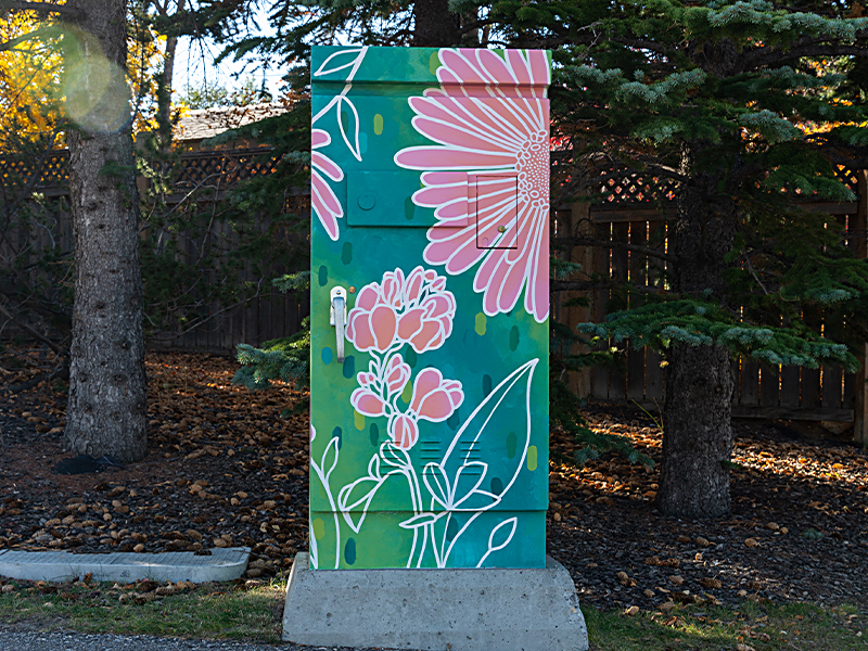 A utility box painted with large pink flowers and green leaves, set against a green background.