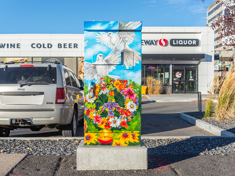 Utility box mural with white doves, colourful flowers, and a candle.