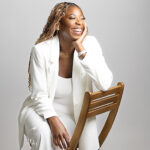 Priscille Bukasa wearing a white suit sitting on chair