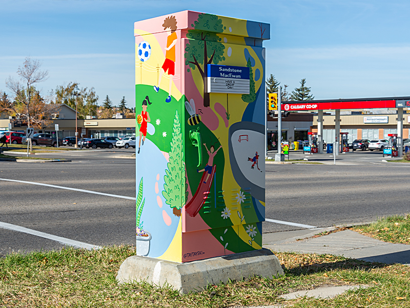 Utility box painted with children playing sports, a slide, and various outdoor scenes.