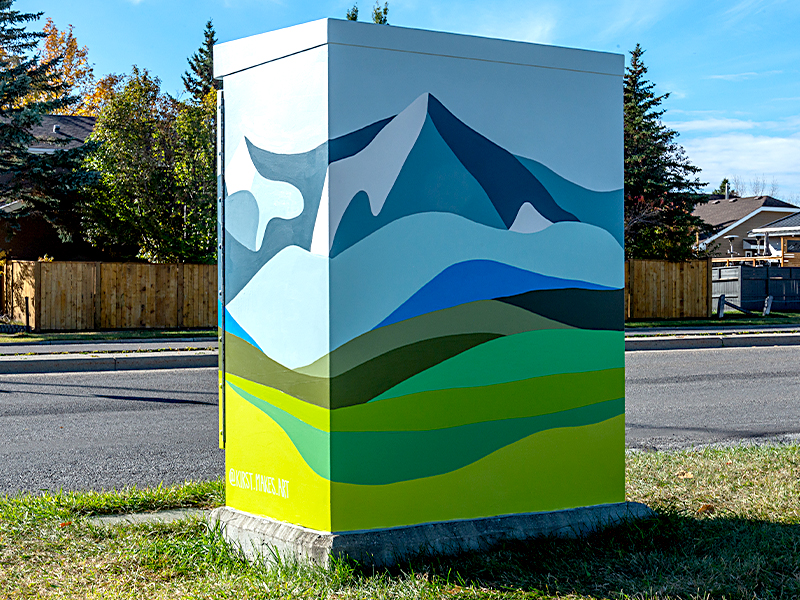 Utility box painted with a landscape featuring mountains in shades of blue and green, against a light sky. The bottom half has green hills.