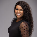 Wunmi Idowu wearing a black top standing against a grey backdrop