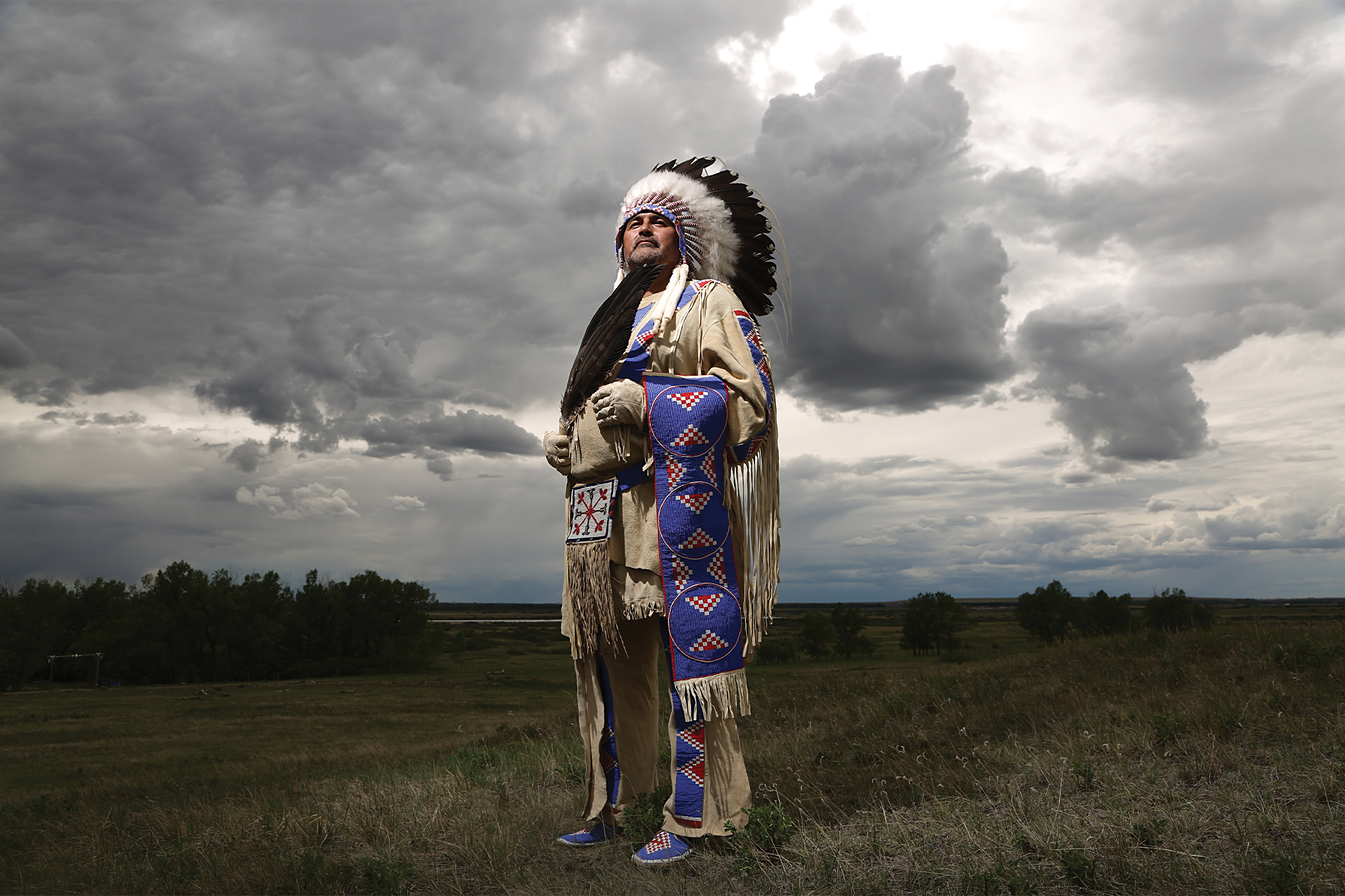 Photograph of Adrian Stimson in front of a stormy grey sky landscape