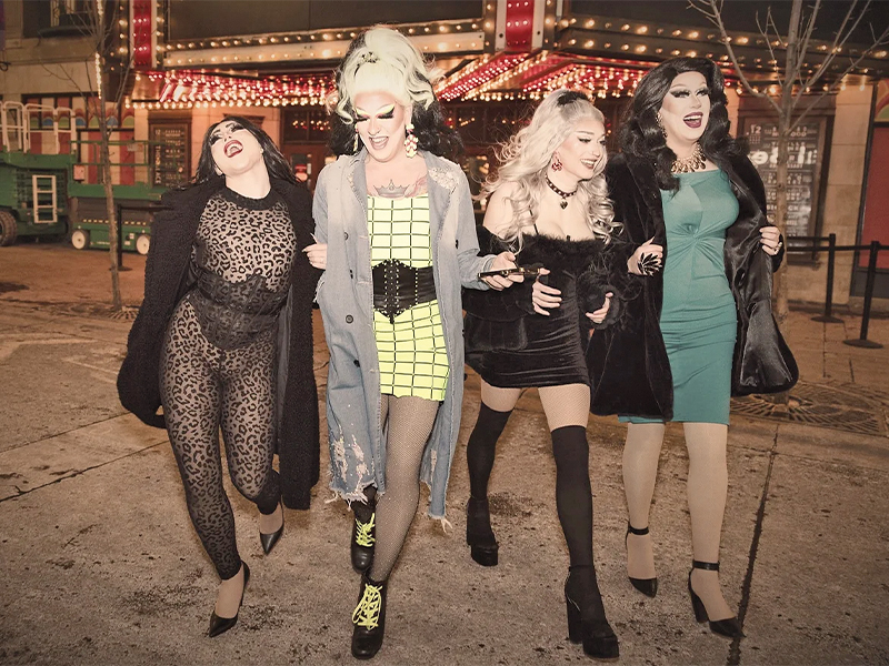 Local drag performers walking on the street with expressions of fun