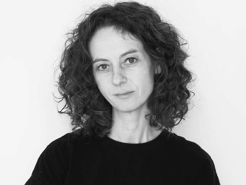 Alexis Kinloch wearing a dark tshirt with dark, wavy hair in a black and white headshot
