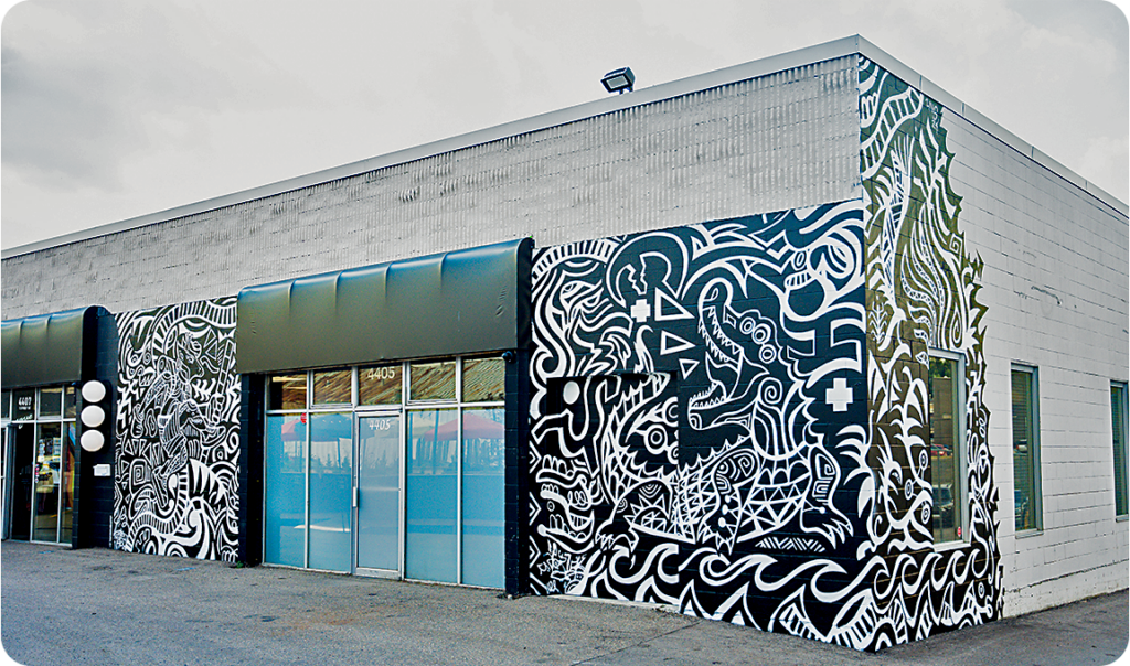 A strip mall building with public art mural wrapping the one-story building