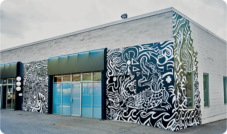 A strip mall building with public art mural wrapping the one-story building