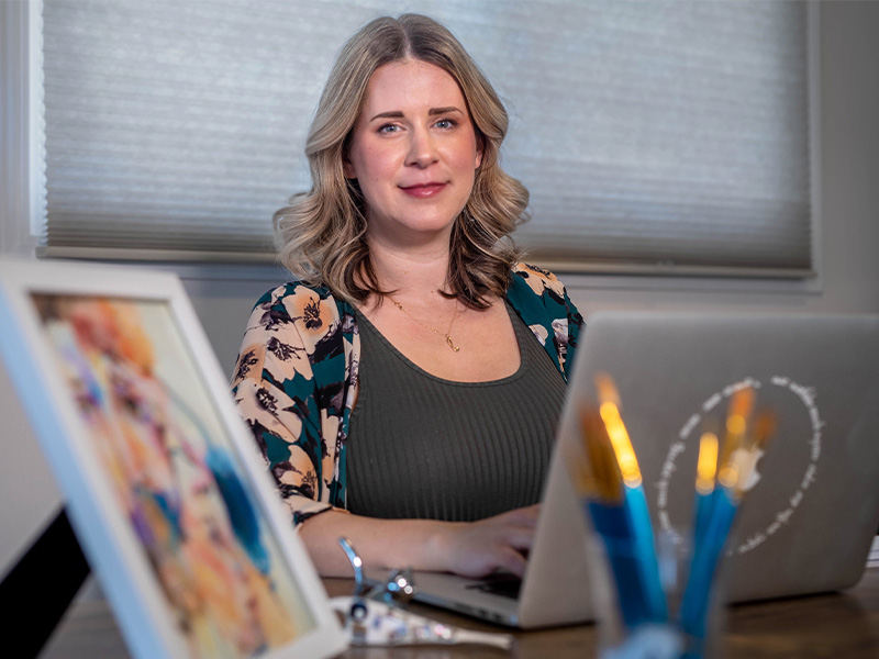 Melissa Skowron sitting behind a computer at a desk in what looks like a classroom