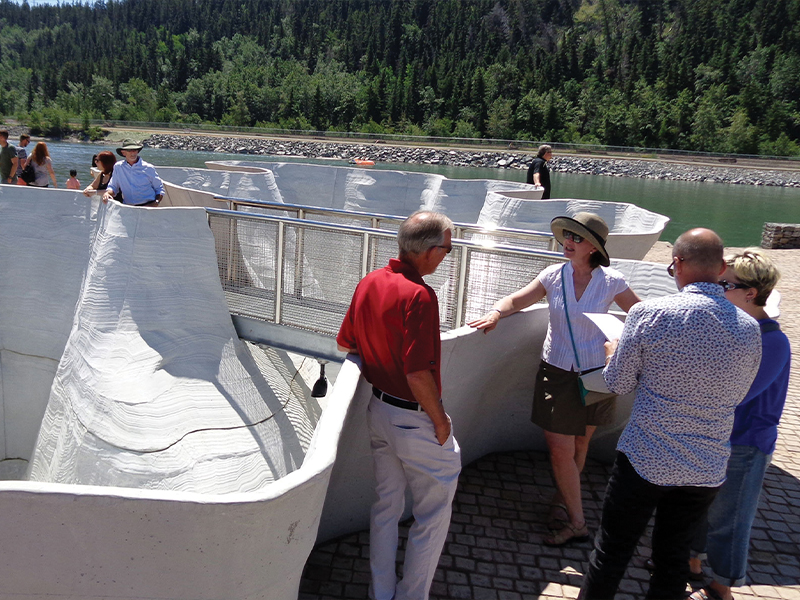 Wavy forms by the Bow River with people standing discussing them | Outflow Glacier by Brian Tolle