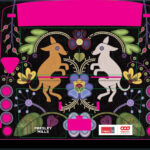 The back of a city bus decorated with Presley Mills’ embroidery-inspired illustration. Two dogs, one golden and one white, face each other symmetrically above a large purple flower. Surrounding them are symmetrical floral and leaf patterns in bright green, yellow, pink and blue against a dark background. At the bottom, logos for Calgary Arts Development and the City of Calgary appear alongside the artist's name.