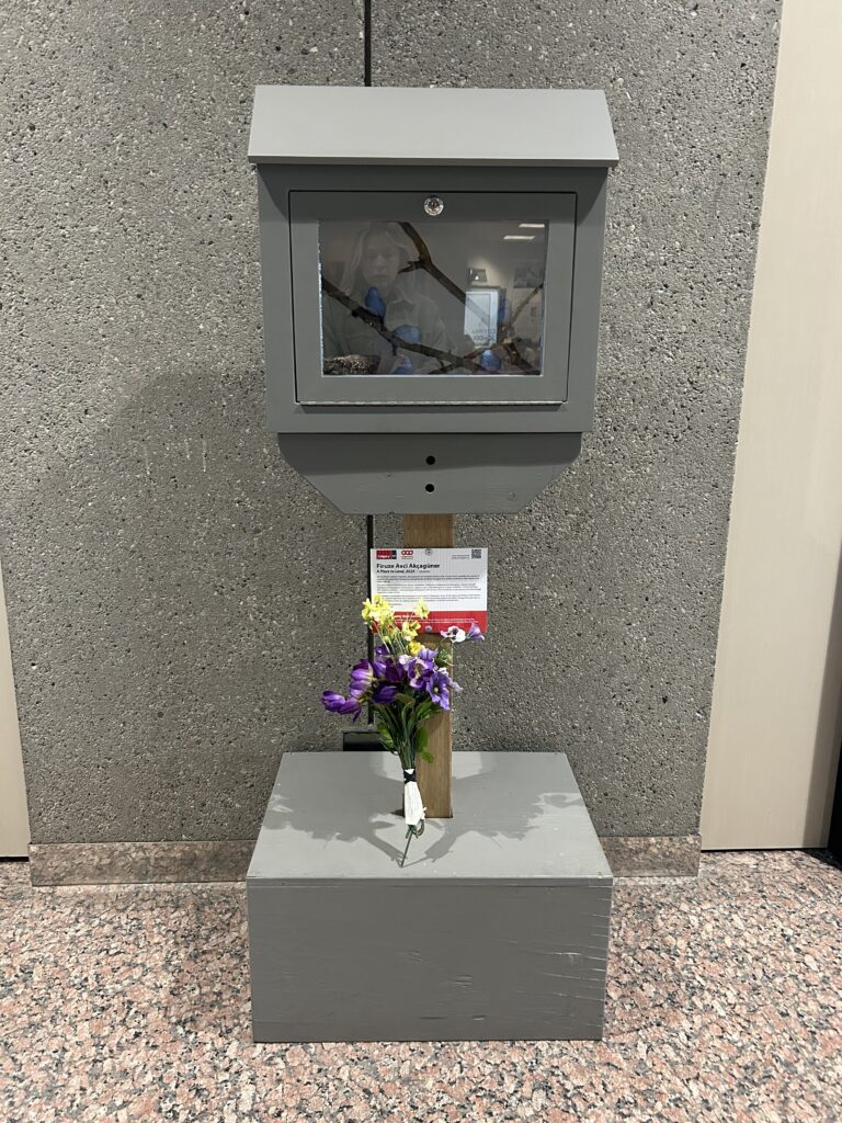 A mini gallery with artwork inside and an info card attached to the vertical post.