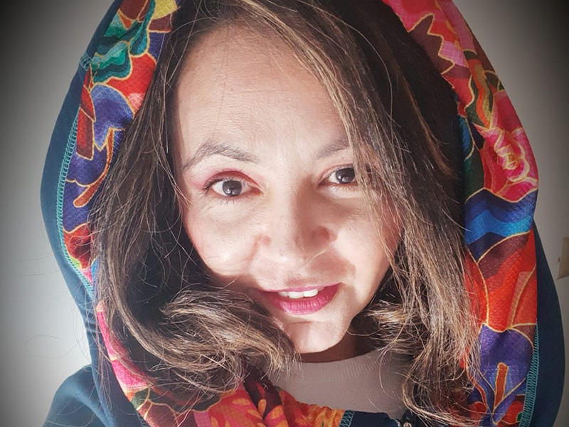 Lily Sigie in a multi-coloured hood with brown hair framing her face