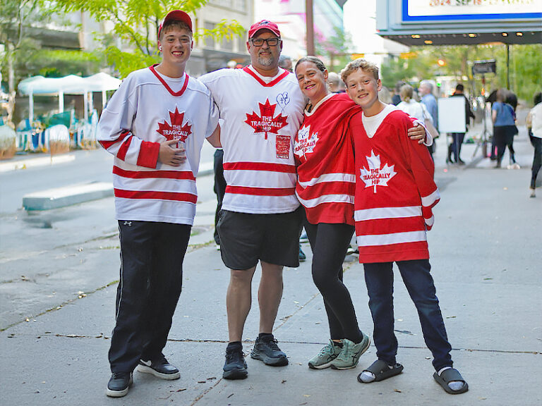 A family in team Canada hockey jersey's outside a cinema, looking happy during the 2024 Calgary International Film Festival