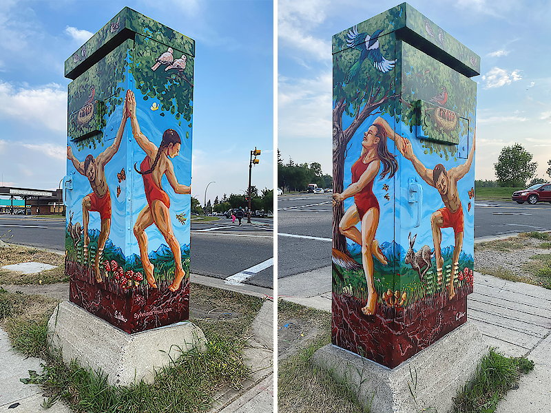 A painted utility box shows two people in red swimsuits reaching out to each other in an outdoor setting, with trees, animals and birds surrounding them.