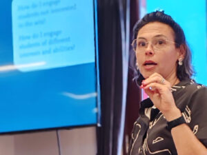 Aliza Sarian speaks in front of a screen as if giving a presentation