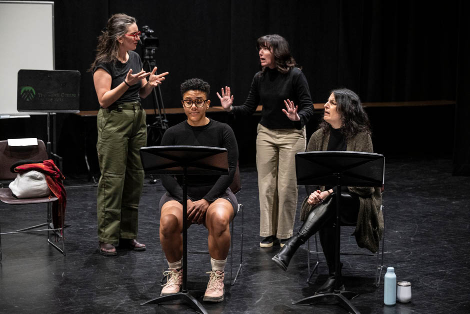 Performers and what looks like teachers and students looking at reading stands on a stage.