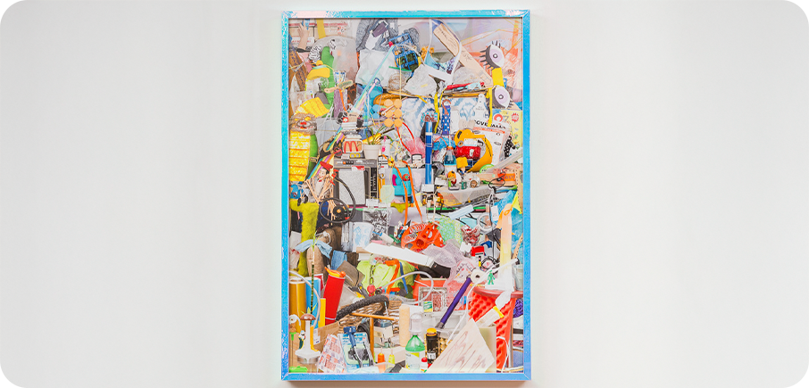 A colourful collage-style artwork made from many layered images and objects, framed and hung on a white wall.