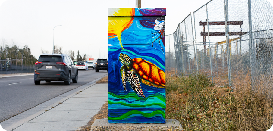 A utility box painted with a colourful underwater scene featuring a sea turtle swimming through blue and green waves, with a bright sun.