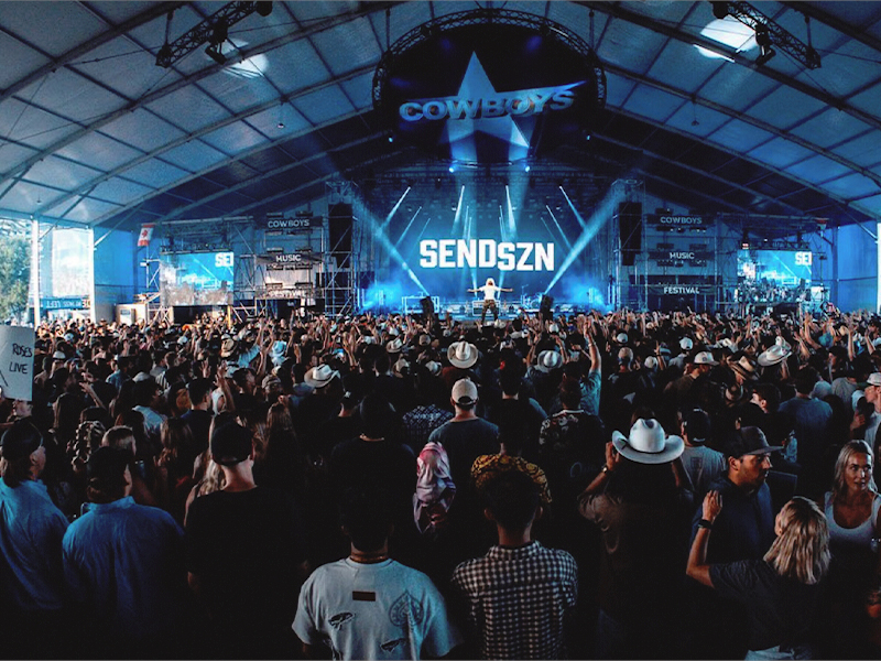 Image of a stage with a large audience in a marquee style performance at Cowboys
